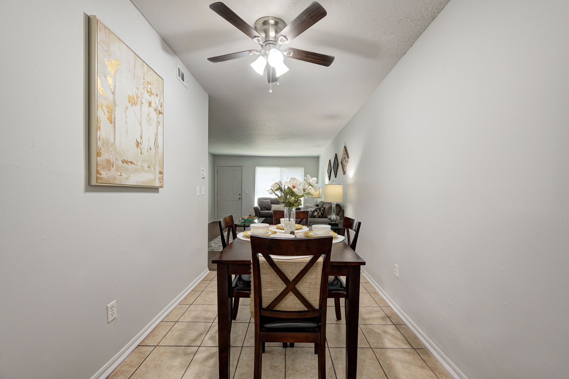A dining room with a table and chairs and a ceiling fan.