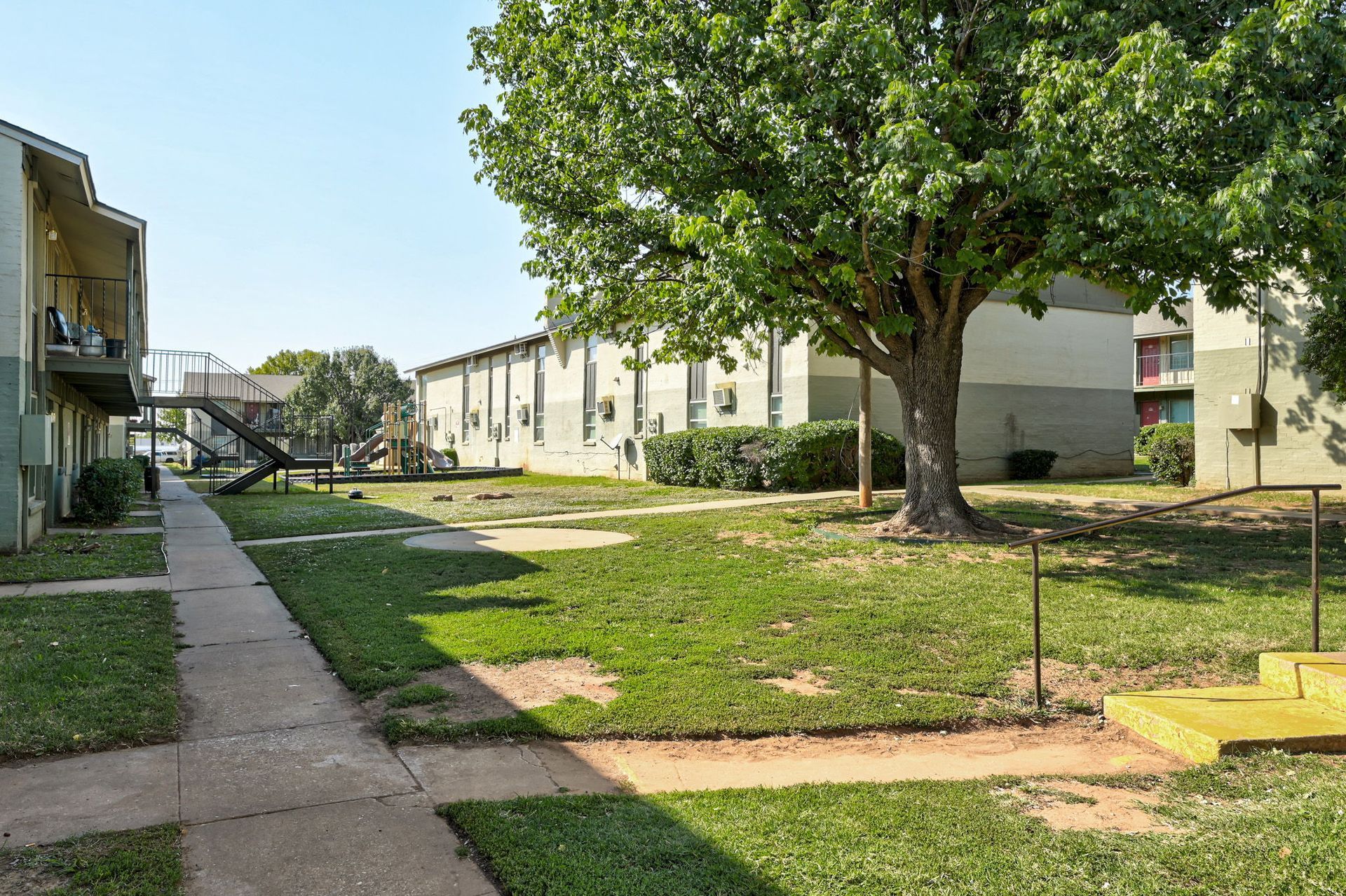 A row of apartment buildings with a tree in the middle of the courtyard.