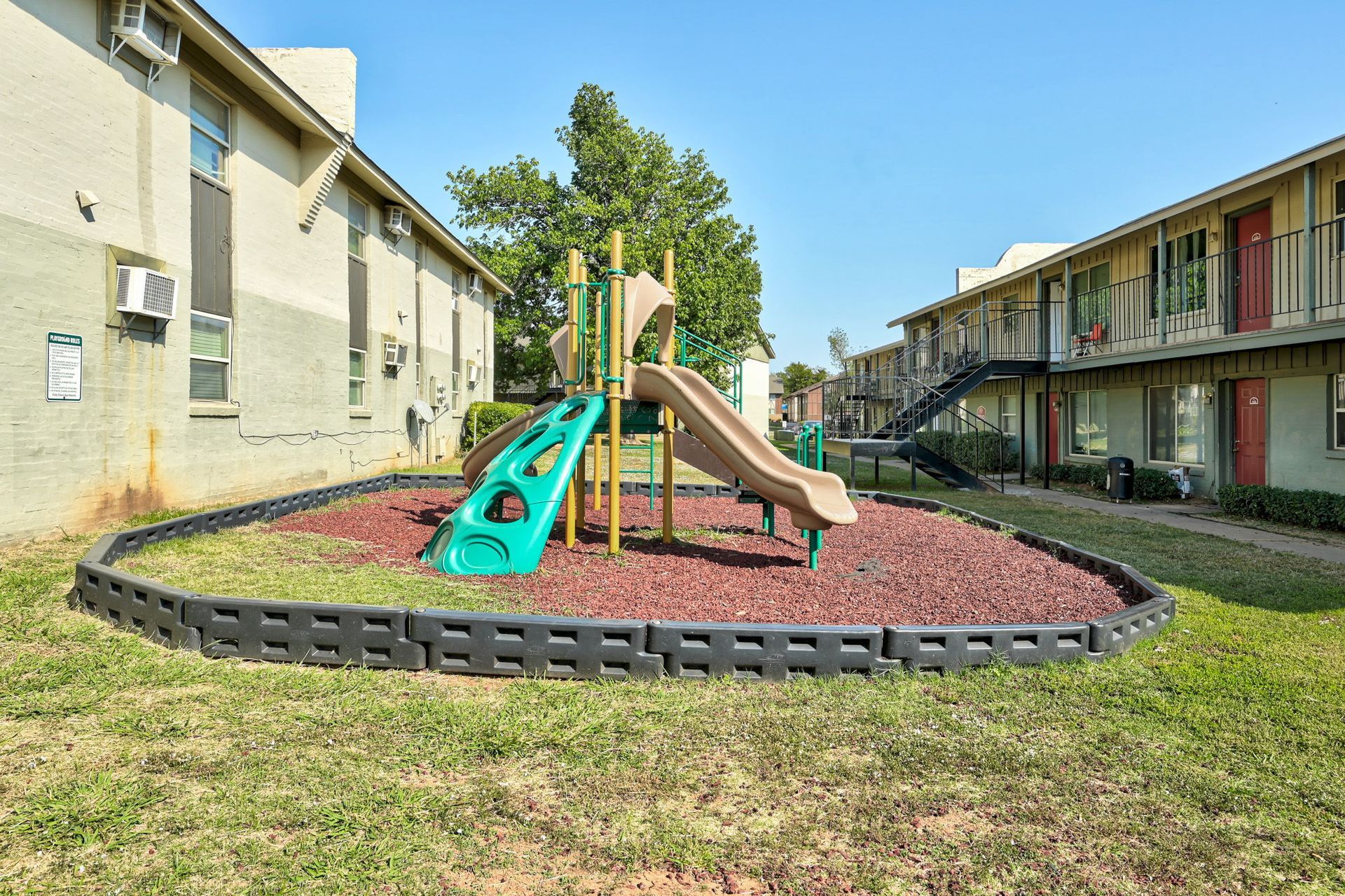 A playground with a slide and a slide in front of a building.