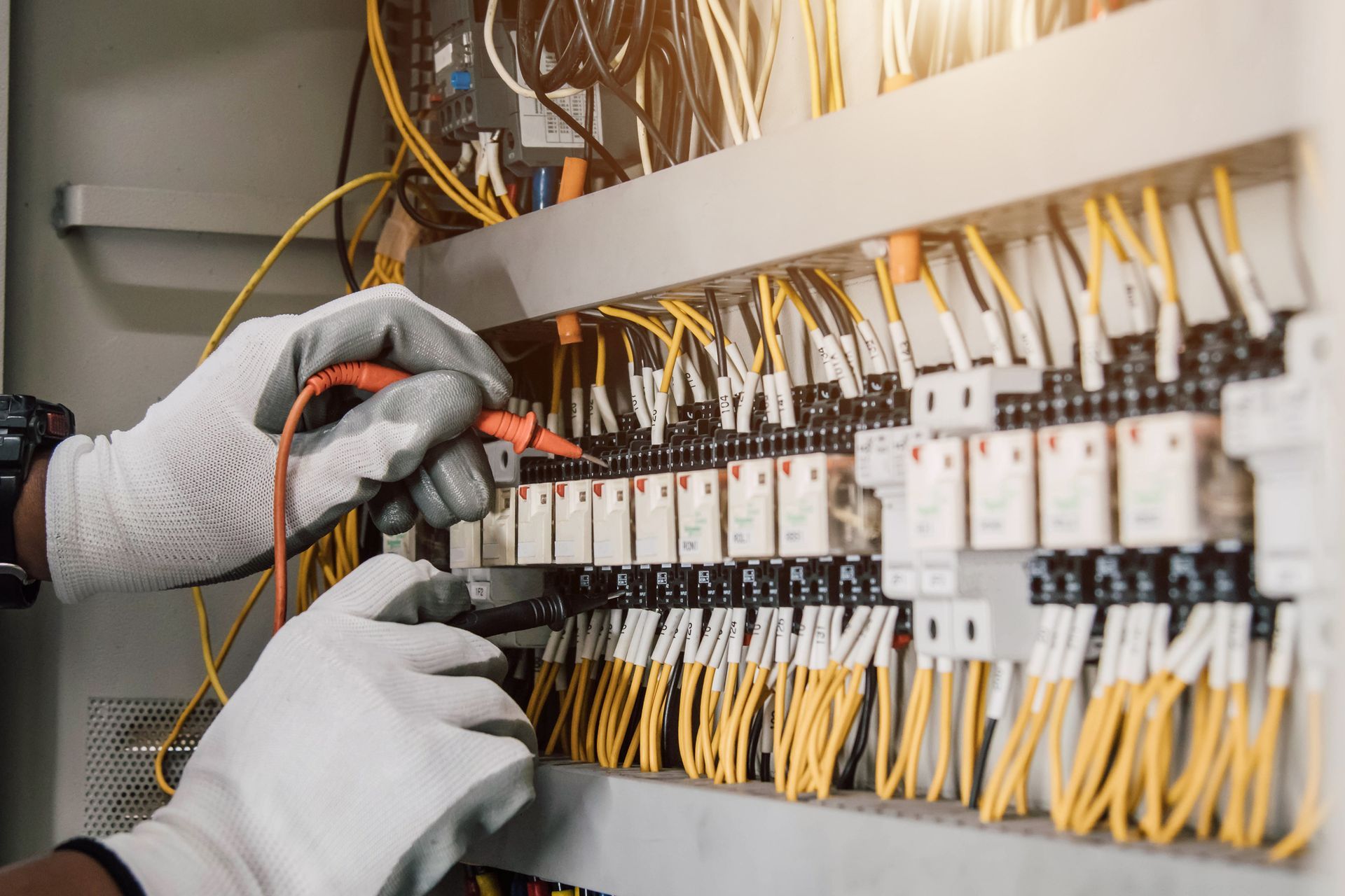 Un elettricista sta lavorando su un quadro elettrico con un multimetro.