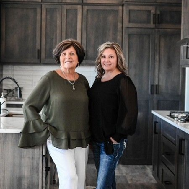 A man is holding a dog in his arms and the dog is wearing a sweater.