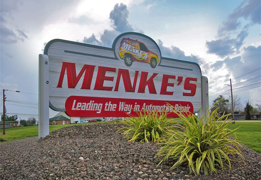 Menke's auto repair sign with red letters, a car graphic, and 