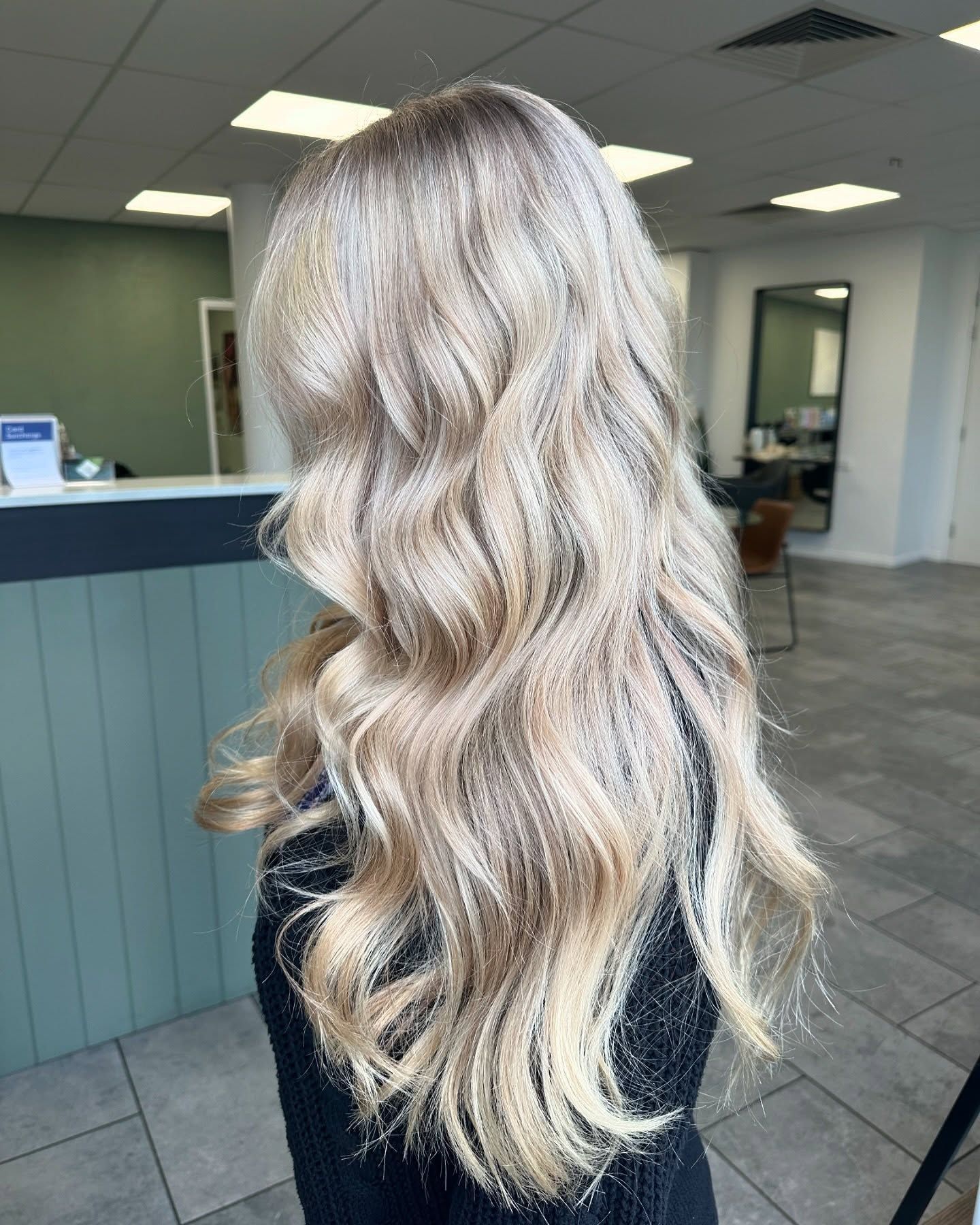 A Woman With Long Blonde Hair is Wearing a Grey Shirt — Fusion Hair In Woree, QLD