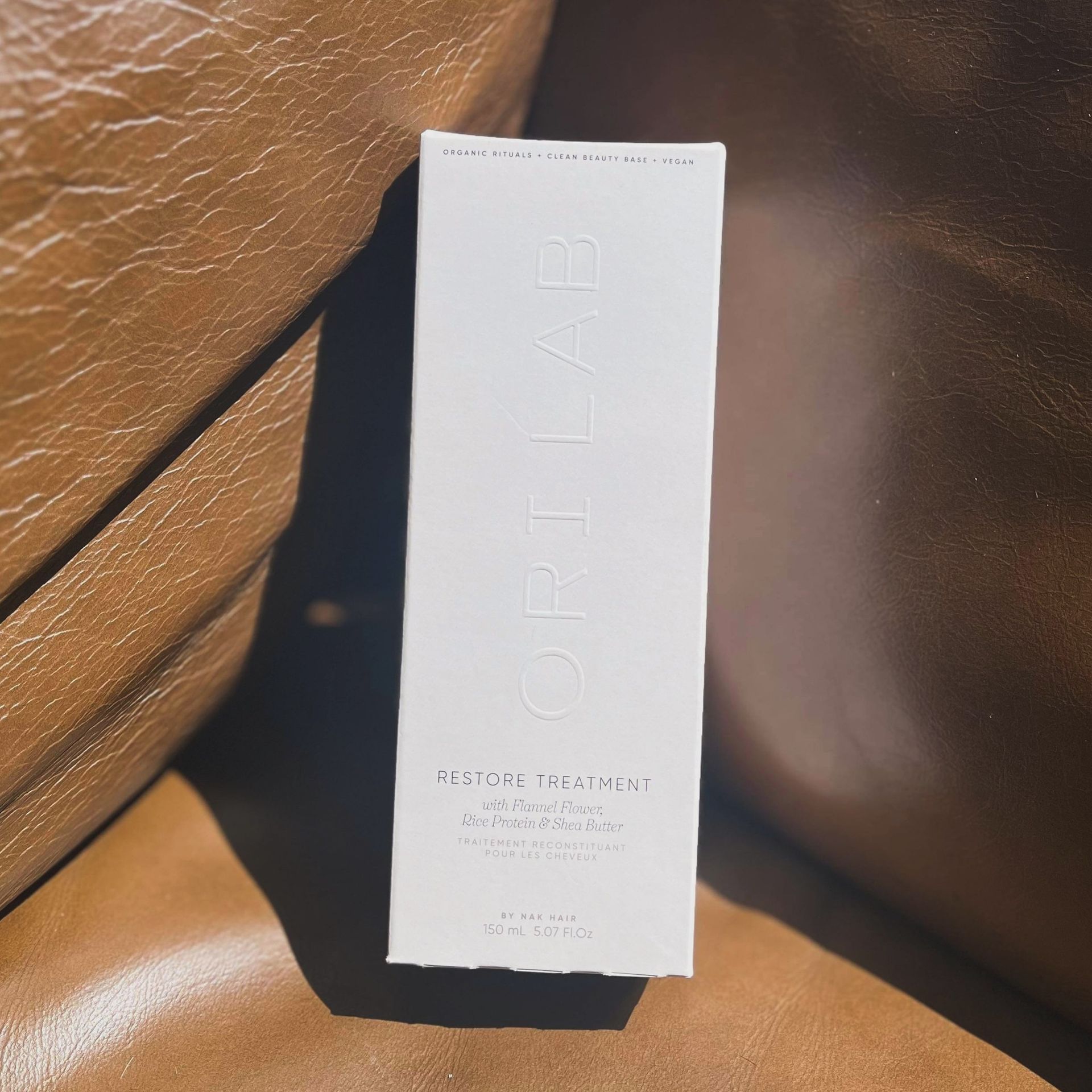 A white box of Ori Lab hair product is sitting on a brown leather chair — Fusion Hair In Woree, QLD