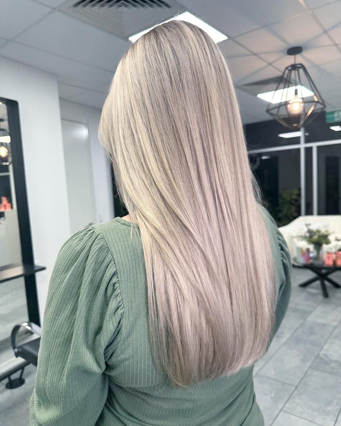 A woman with long blonde hair is standing in a salon — Fusion Hair In Woree, QLD