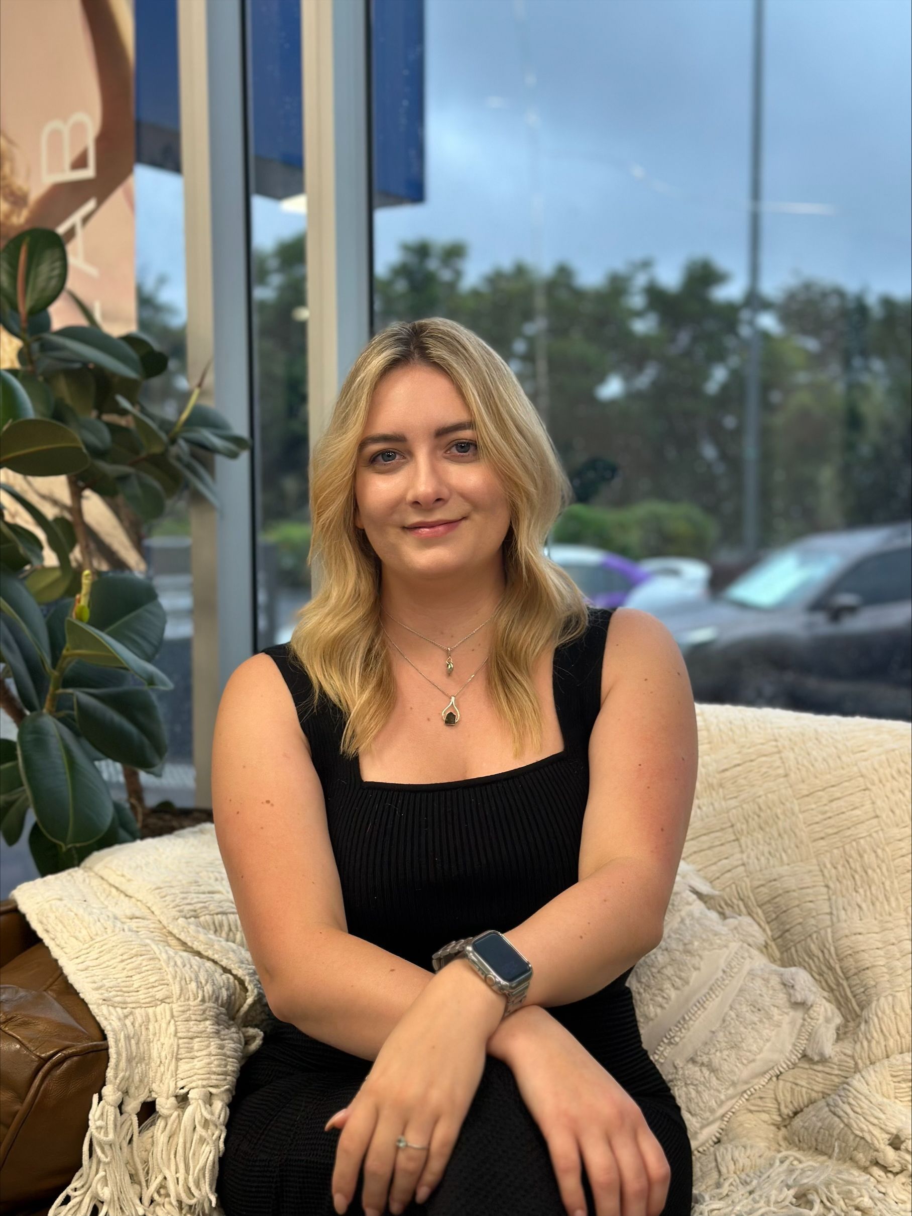 A woman in a black dress is sitting on a couch — Fusion Hair In Woree, QLD