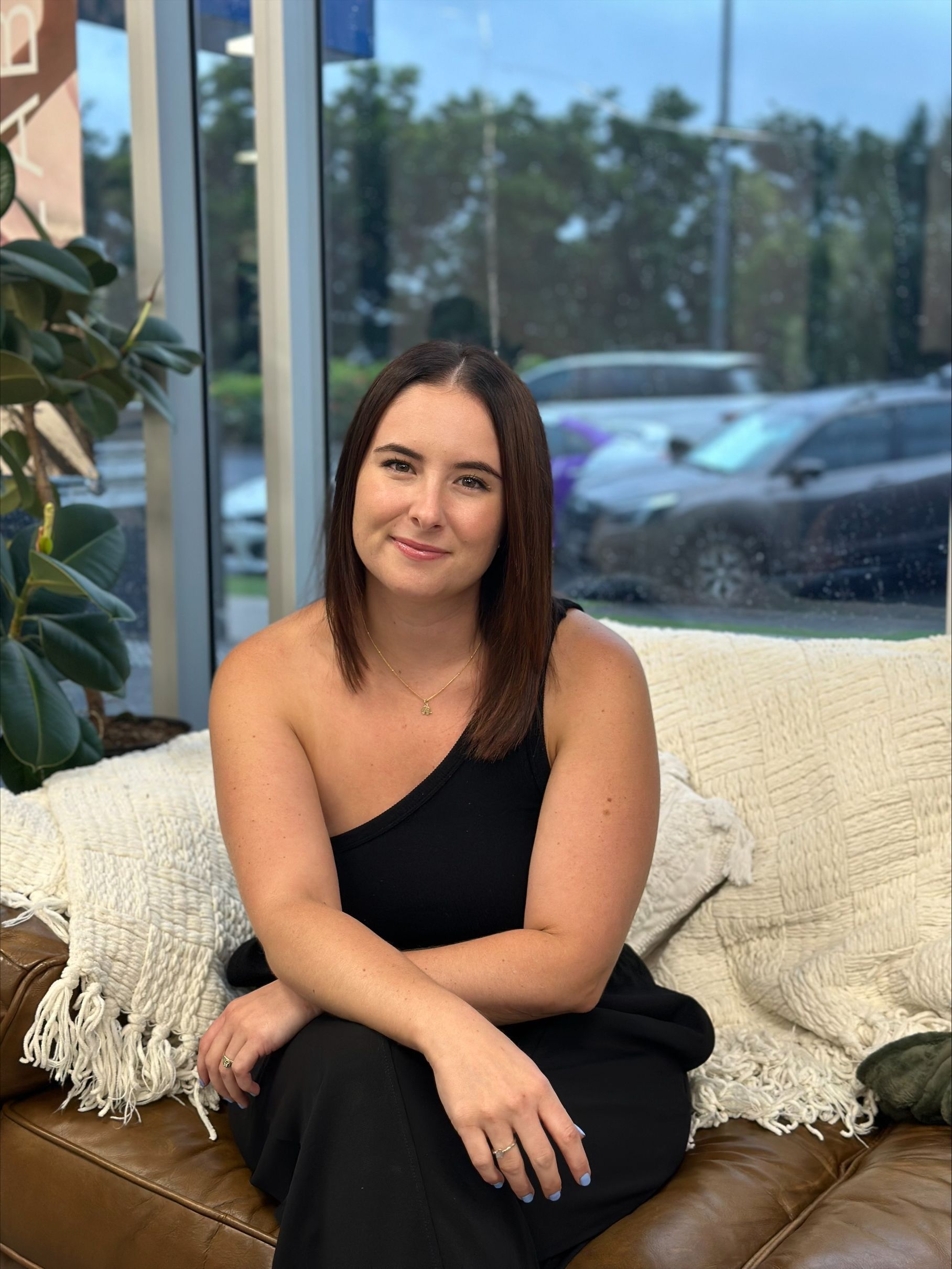 A woman in a black dress is sitting on a couch — Fusion Hair In Woree, QLD