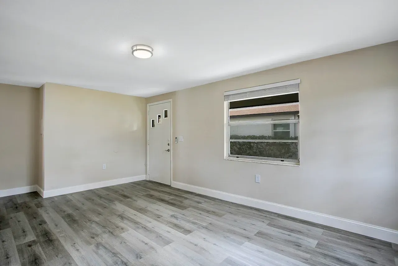 An empty living room with hardwood floors and a window.