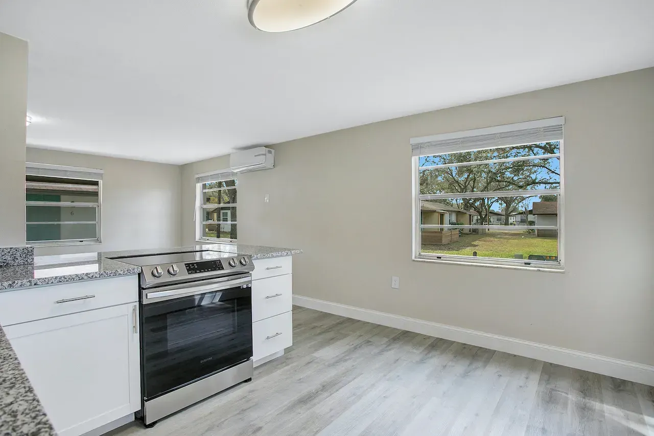 An empty kitchen with a stove and a window.