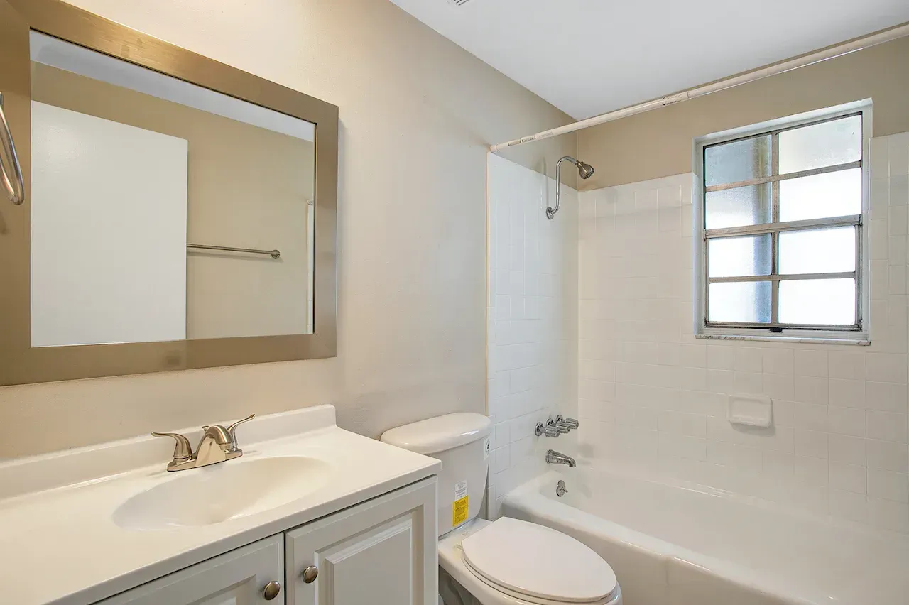 A bathroom with a sink , toilet , tub and mirror.