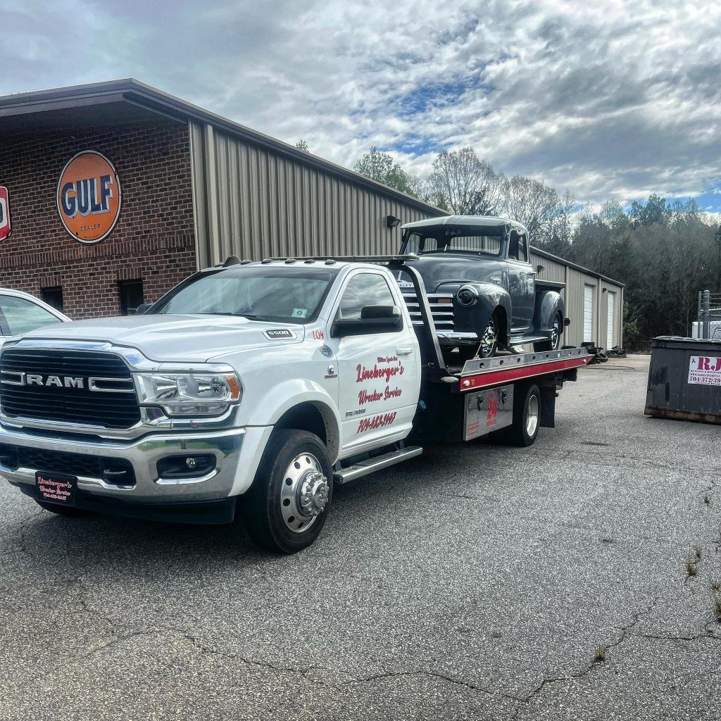 A tow truck is towing a car in front of a building.