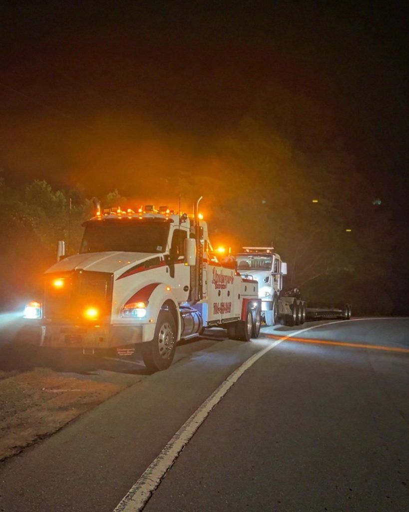 A tow truck is driving down a road at night.