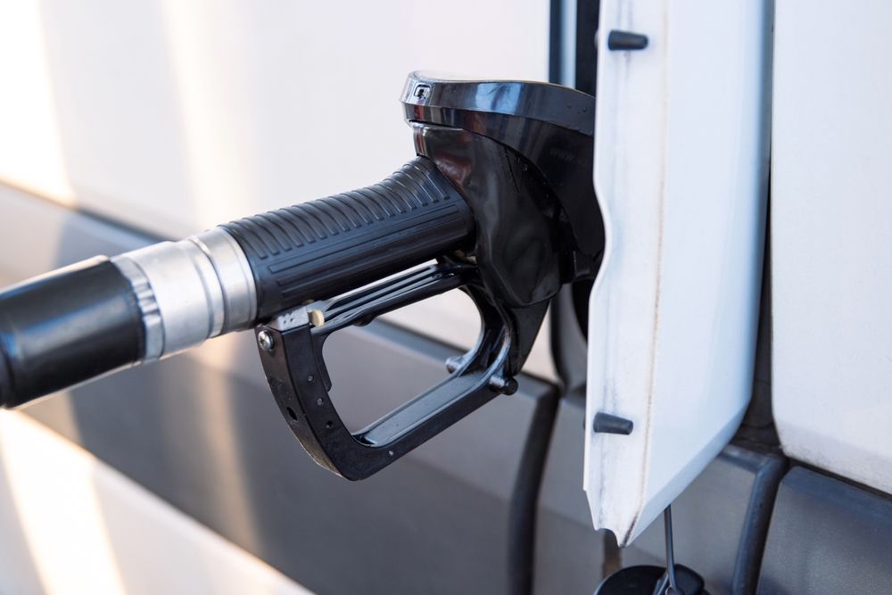 A white tow truck is towing a white car in a parking lot.