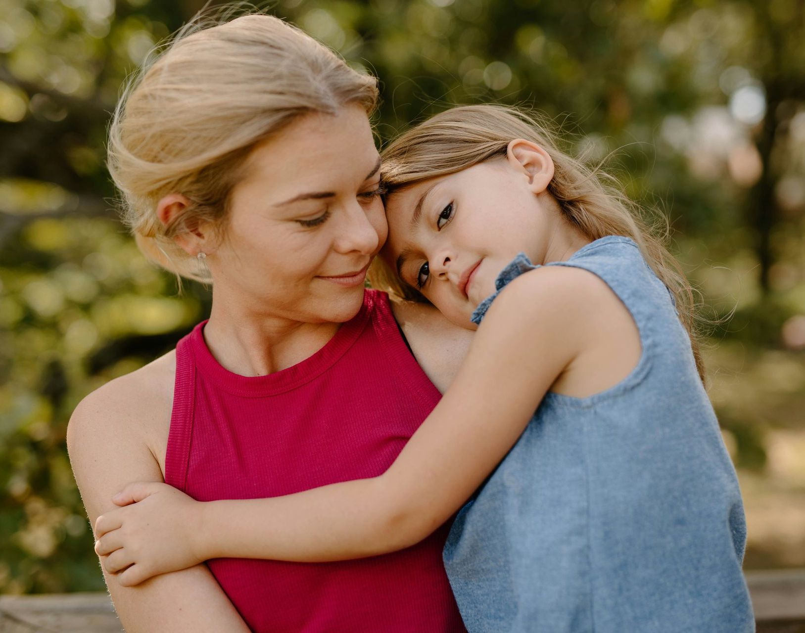 A woman and a little girl are hugging each other.
