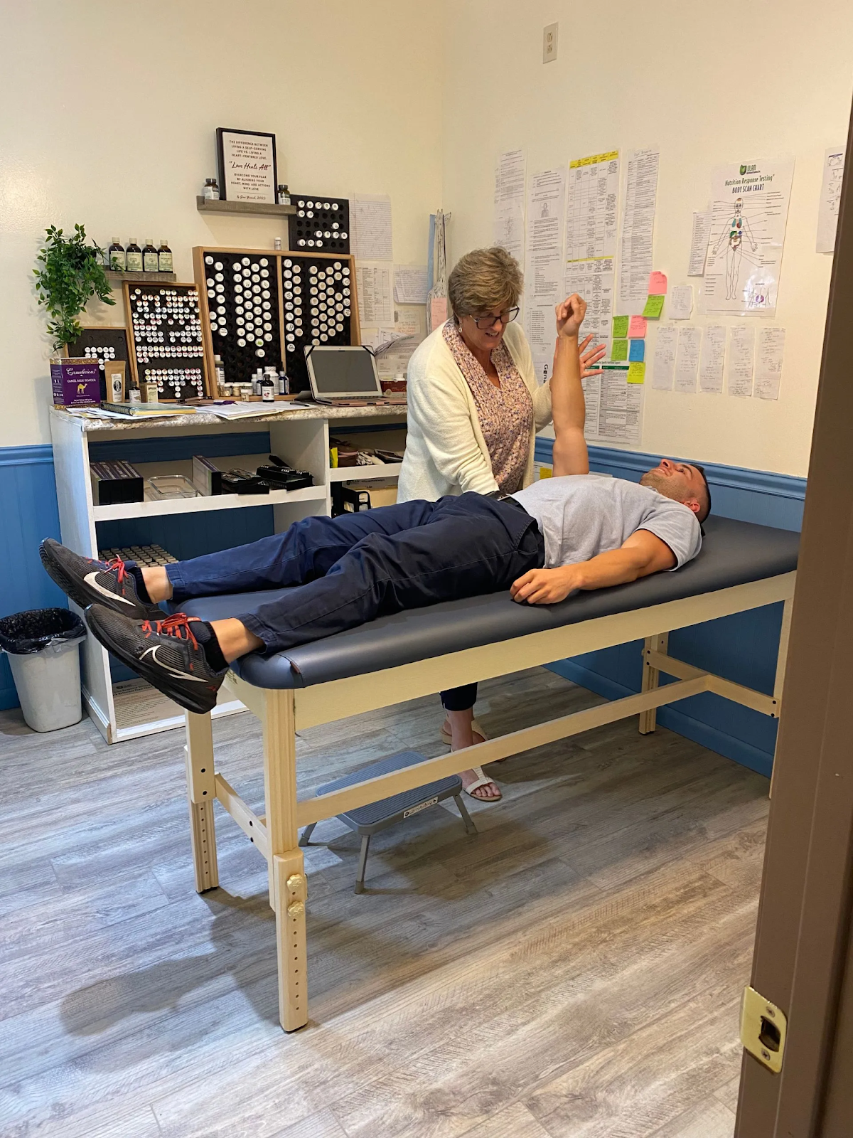 A man is laying on a table while a woman examines his arm.