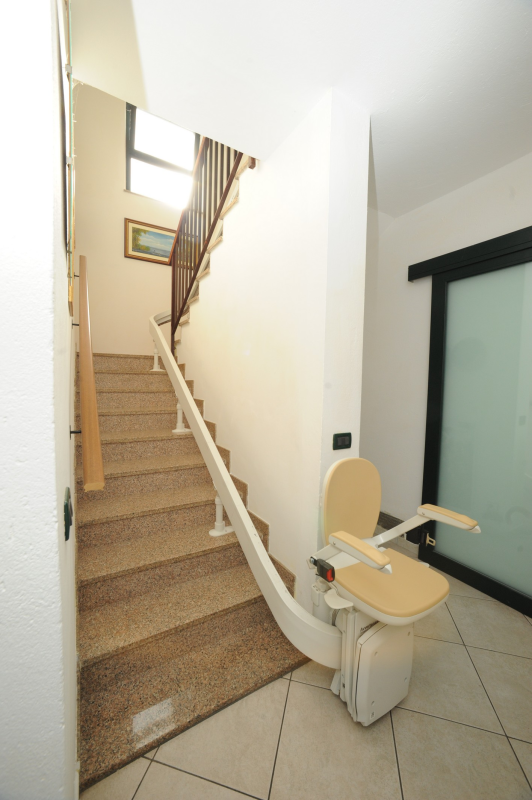 Montascale installato su una scala, sedia beige.