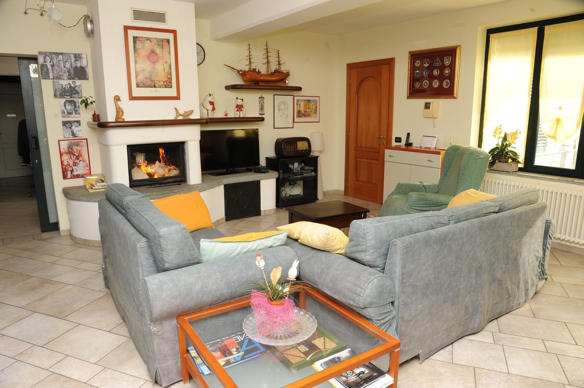 Accogliente soggiorno con camino, divano componibile grigio e tavolino da caffè in vetro.