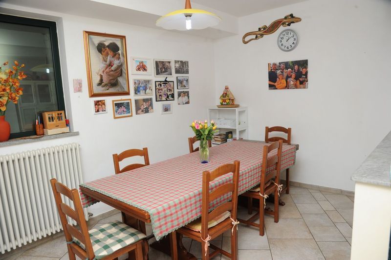 Sala da pranzo con tavolo in legno, sedie e foto di famiglia alla parete.