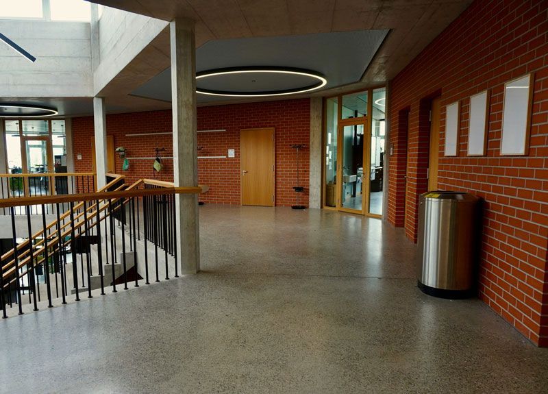 An empty hallway with a staircase and a trash can
