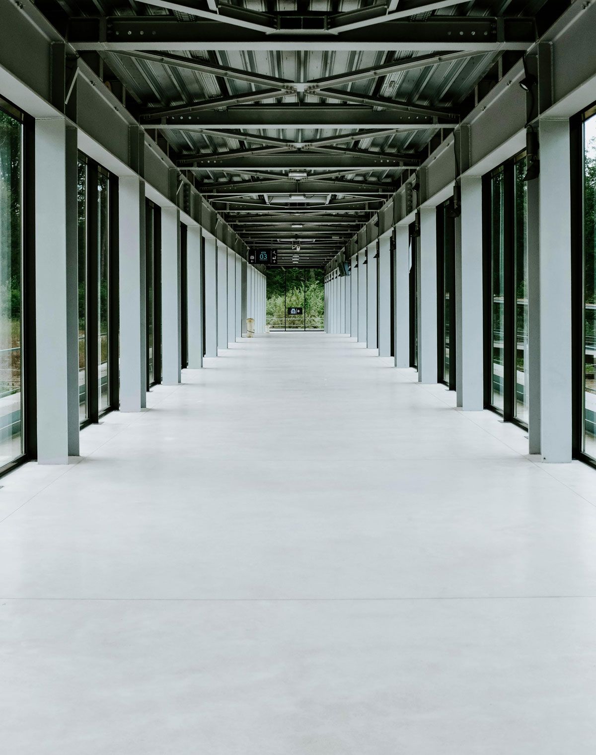 A long empty hallway with a lot of windows and columns.