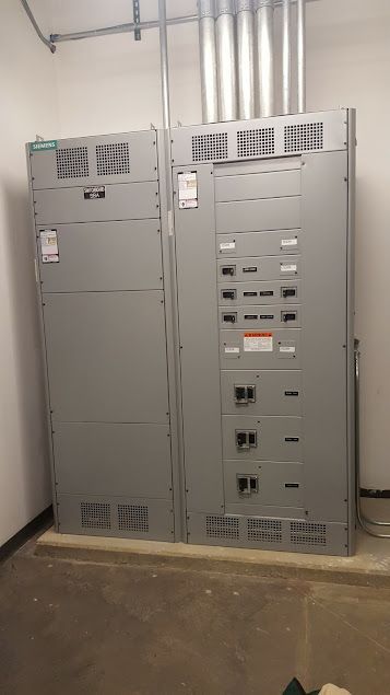 Mend Electric LLC - Two electrical panels are sitting next to each other in a room.