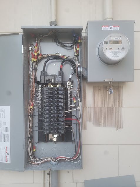 Mend Electric LLC - A electrical panel with a meter attached to it is hanging on a wall.