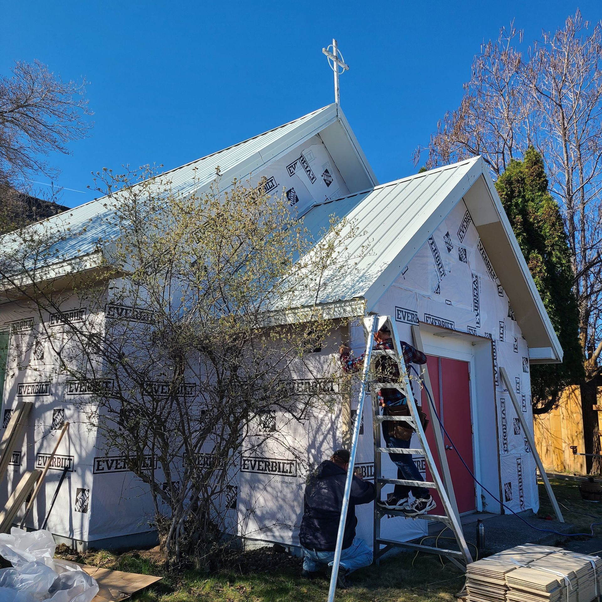 A person on a ladder preparing the church for new siding