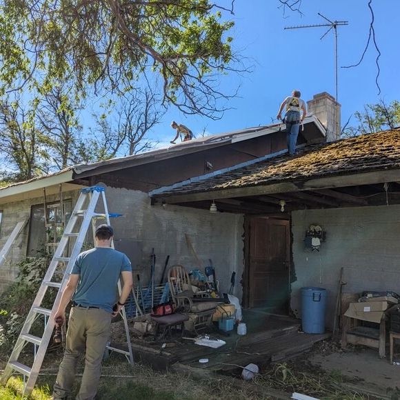 Volunteers are working on the roof of a house in their community in need of repairs.