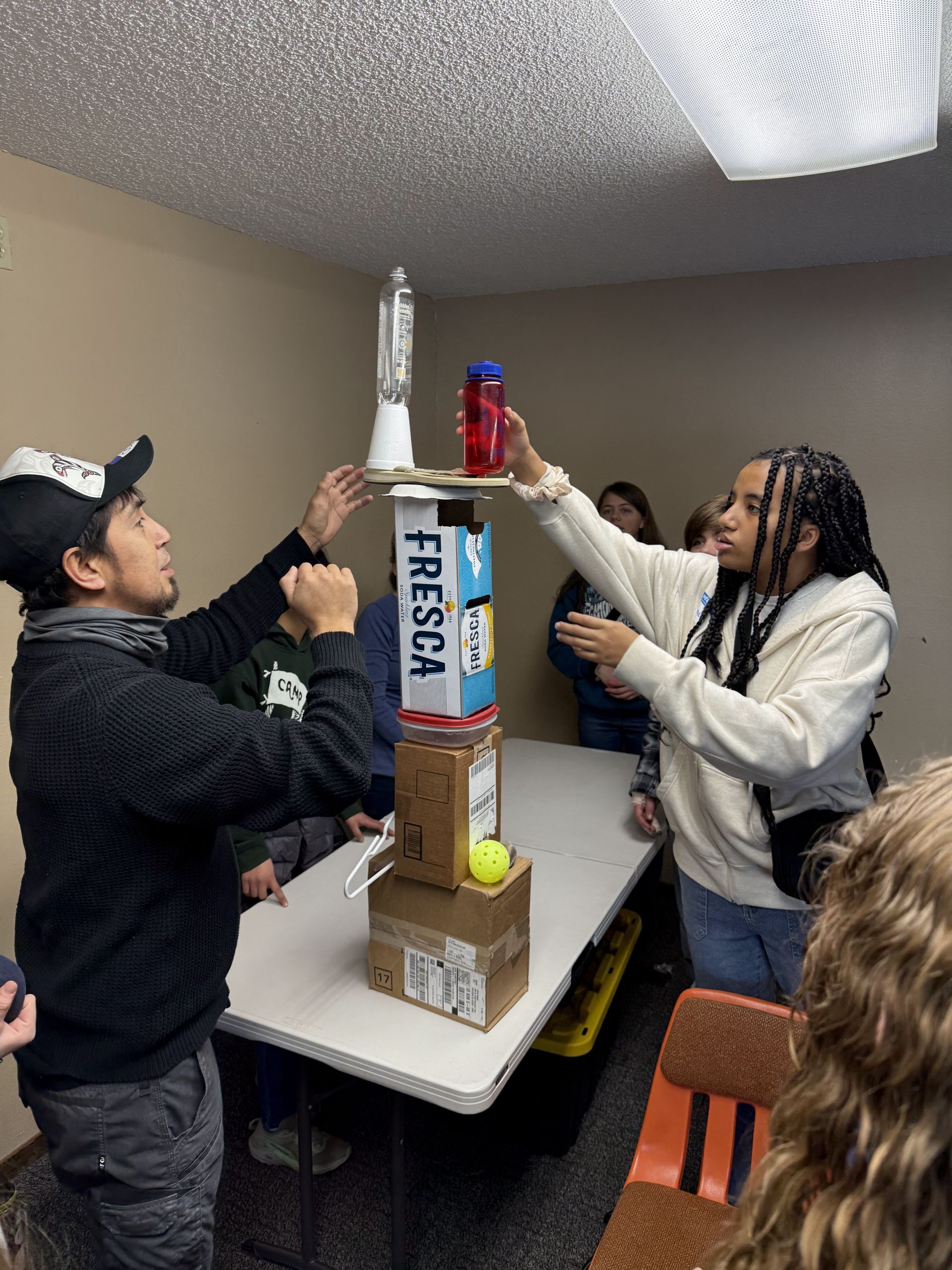 Teens work together to make a tower out of boxes.