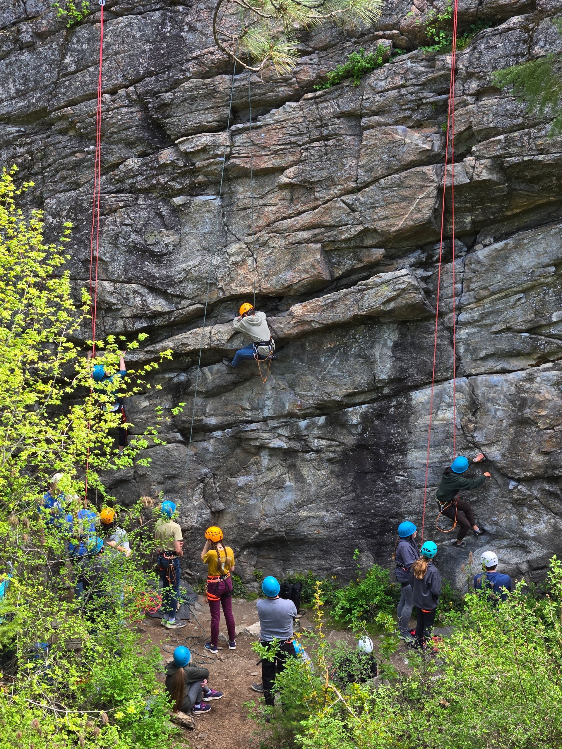 A group of teenagers are climbing a rock wall.