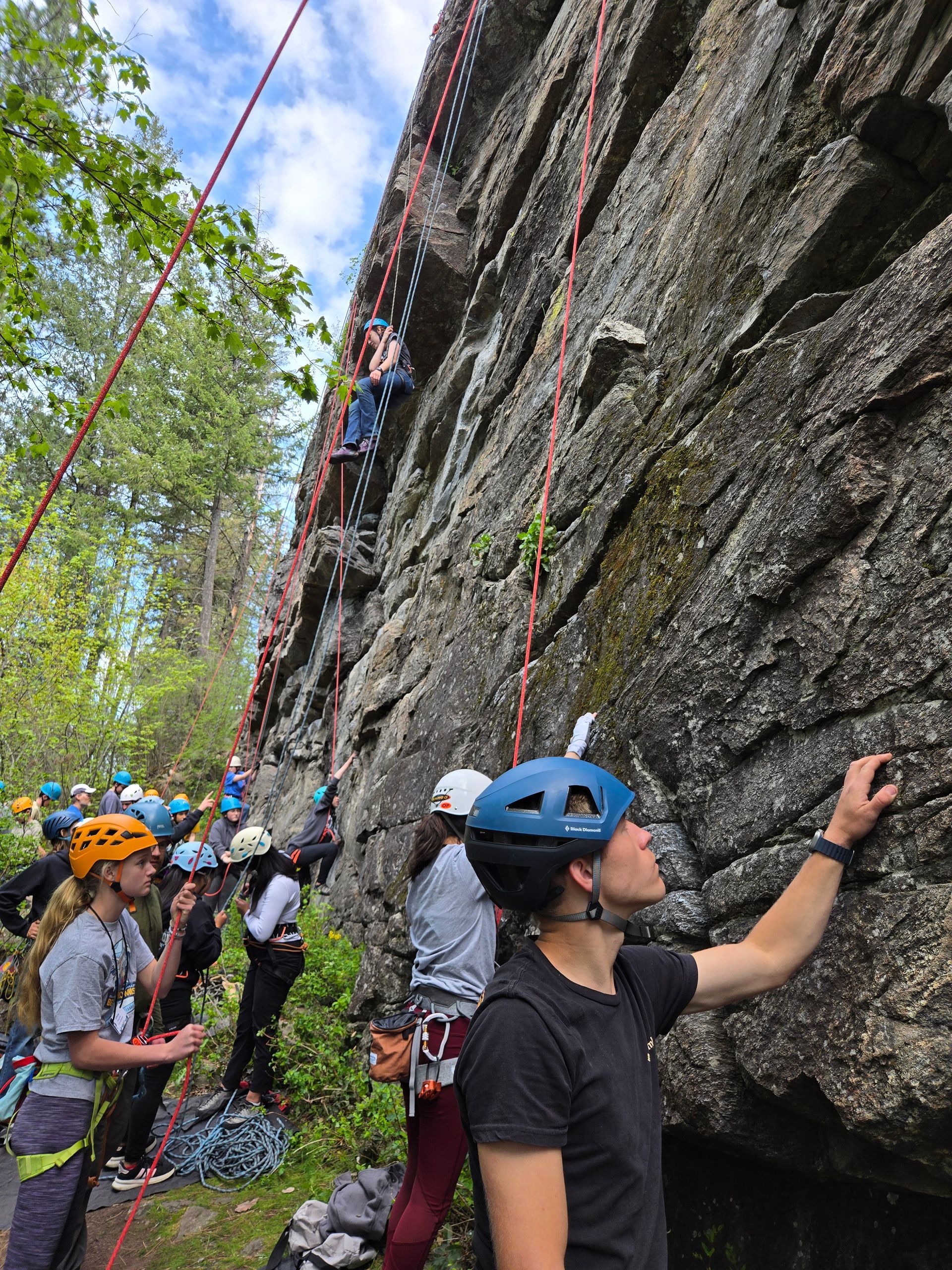 A teenager starting his ascent up a rock wall.