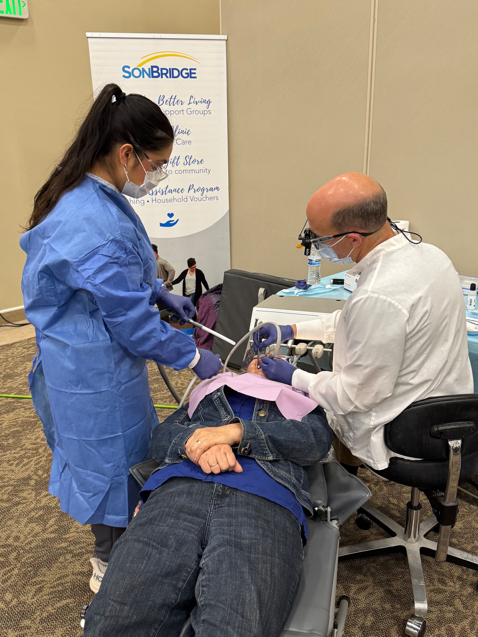 A woman is sitting in a chair getting her teeth examined by a dentist.