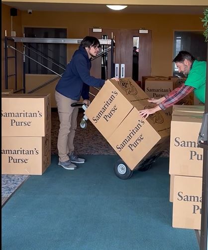 A man is pushing a cart full of boxes labeled samaritan 's purse