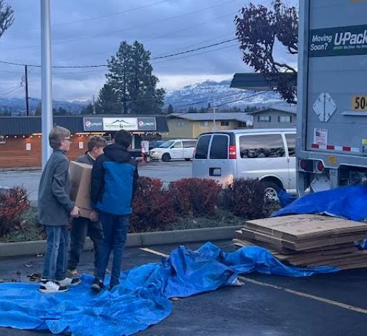 A group of people carrying a box of donations towards a parked truck.