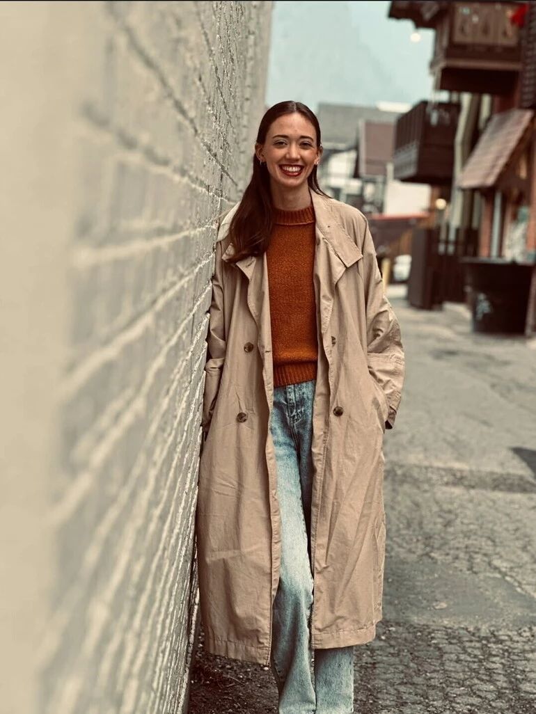 Halle Gates leans against a brick wall, smiling