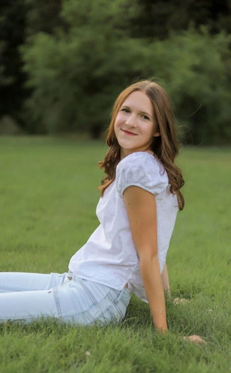 Kaitlyn Rivas smiling seated in a field of grass