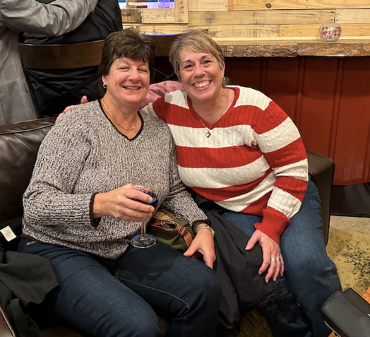 Two women are posing for a picture while sitting on a couch