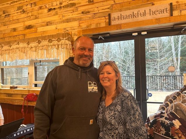 A man and a woman are posing for a picture in front of a thankful heart sign.