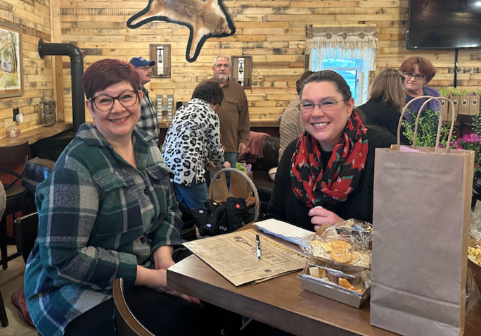 Two women are sitting at a table in a restaurant.