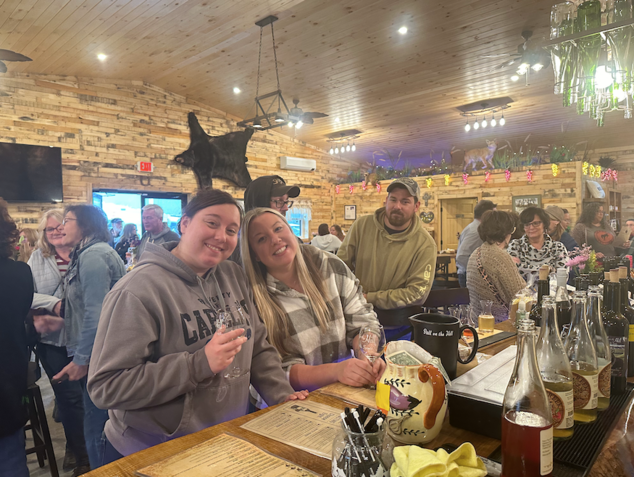 A group of people are standing around a bar.