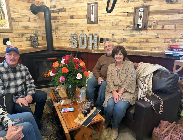 A group of people are sitting around a table in a living room.
