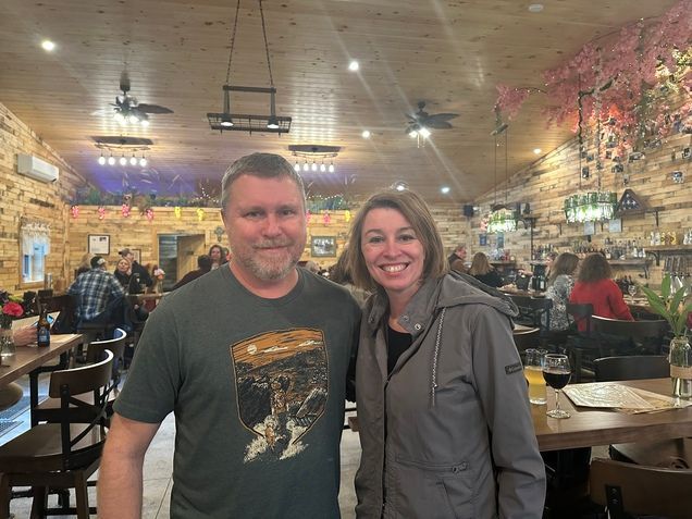 A man and a woman are posing for a picture in a restaurant.
