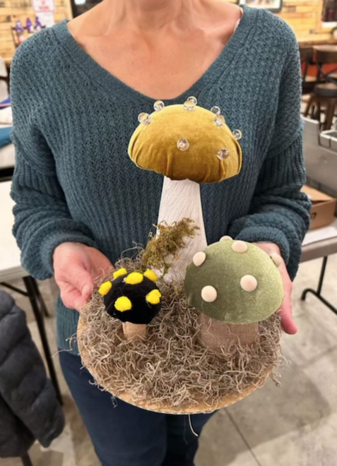 A woman is holding a plate with three mushrooms on it.