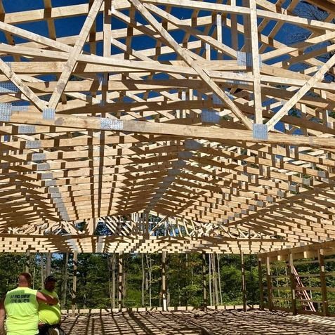 A large wooden structure is being built on a sunny day.