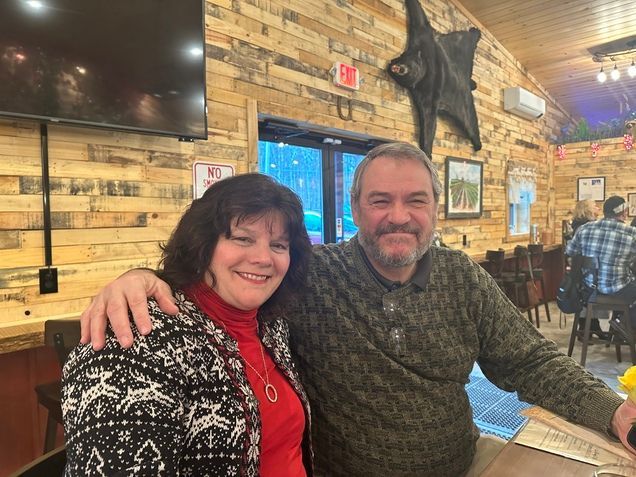 A man and a woman are posing for a picture in a restaurant.
