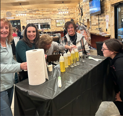 A group of women standing around a table with bottles of liquid on it