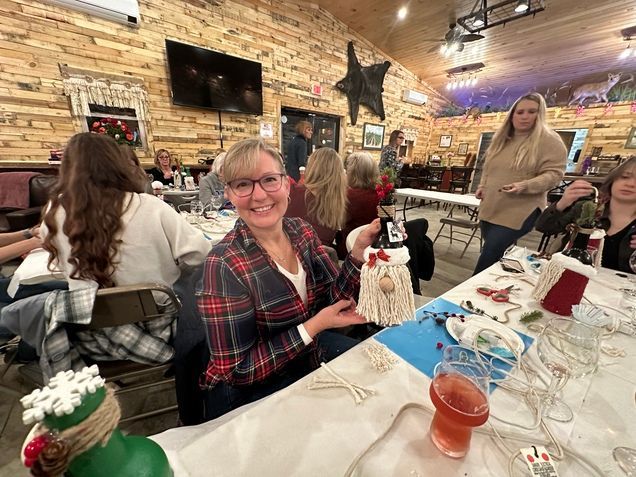A woman is sitting at a table holding a gnome.