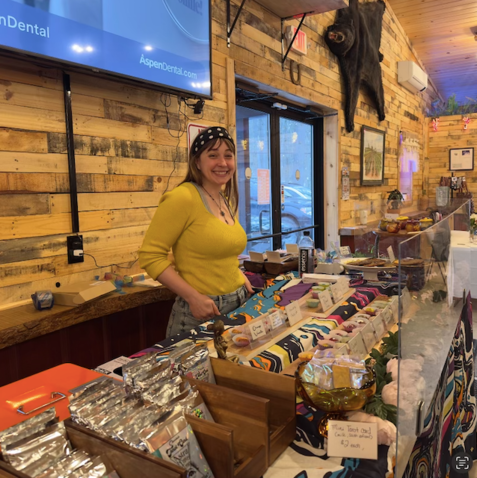 A woman in a yellow shirt is standing behind a counter in a store.
