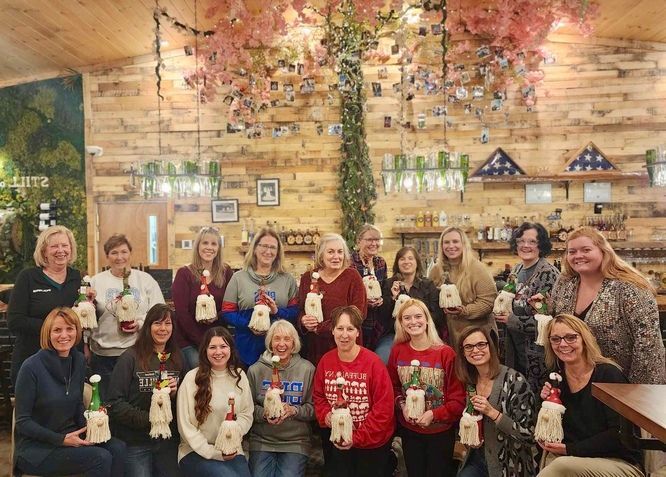 A group of women are posing for a picture in a room holding bottles.