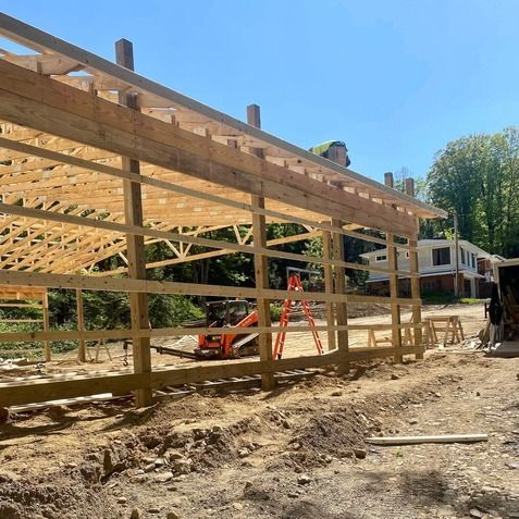 A large wooden structure is being built in a dirt field.